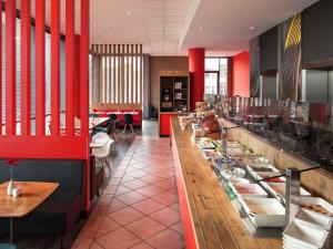 un restaurante con una línea de buffet con mesas y sillas en ibis Hotel Berlin Spandau en Berlín