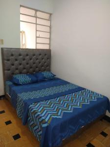 a bed with a blue comforter and blue pillows at Acogedor apartamento en Buga in Buga