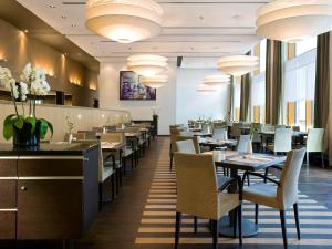 uma sala de jantar com mesas, cadeiras e lustres em Novotel Karlsruhe City em Karlsruhe