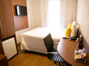 a hotel room with a desk and a bed and a table at Mercure Sao Caetano do Sul in São Caetano do Sul