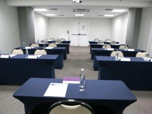 uma sala com fileiras de mesas e cadeiras com uma garrafa em Mercure Sao Caetano do Sul em São Caetano do Sul