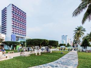 ein Park mit Palmen und ein hohes Gebäude in der Unterkunft Novotel Nha Trang in Nha Trang