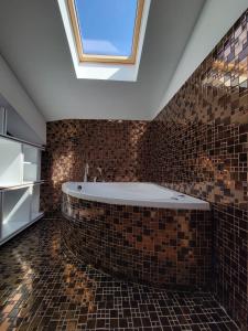 a bathroom with a bath tub with a skylight at Nam Hotel in Prizren