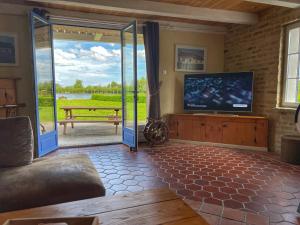 een woonkamer met een tv en een glazen schuifdeur bij Gite du lac du Palentin Ardres in Ardres