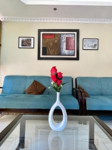 sala de estar con sofá azul y jarrón con rosa en Hostal R. Williams, en Puerto Francisco de Orellana