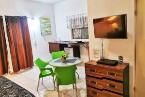 a room with a table and chairs and a television at Depto Perla a 5 mins de playa con alberca y wifi in Cabo San Lucas