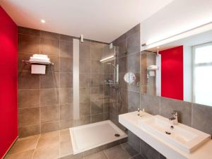 a bathroom with a sink and a shower at Hôtel Mercure Vittel in Vittel