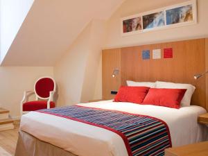 a bedroom with a large bed and a red chair at Hôtel Mercure Vittel in Vittel