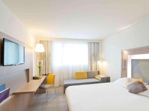 a hotel room with a bed and a desk and a tv at Novotel Lodz Centrum in Łódź