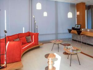 uma sala de estar com um sofá vermelho e um piano em ibis Ourinhos em Ourinhos