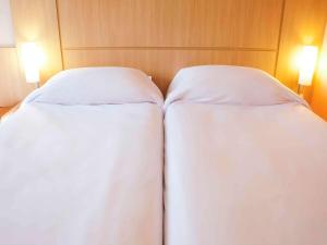 2 camas en una habitación de hotel con sábanas blancas en ibis Ourinhos, en Ourinhos