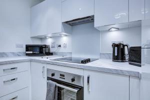 a white kitchen with white cabinets and a sink at Brand New apartment next to Lakeside Shopping mall, Essex in West Thurrock
