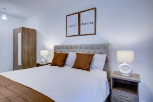 a bedroom with a large white bed with two lamps at Brand New apartment next to Lakeside Shopping mall, Essex in West Thurrock