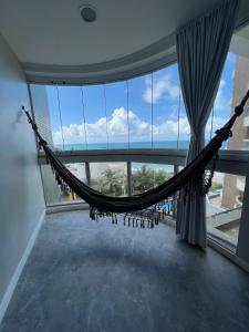 a hammock in a room with a large window at Lindo vista mar na Praia do Buracão - Rio Vermelho in Salvador