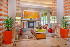 a living room with a fireplace and orange furniture at Hilton Garden Inn St. Louis/Chesterfield in Chesterfield