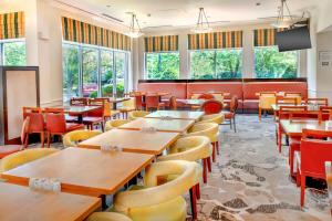 Hilton Garden Inn St. Louis/Chesterfield في تشيسترفيلد: مطعم بطاولات وكراسي ونوافذ