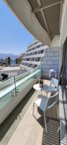 a balcony with a table and chairs and a building at Sweet Sea Side Eilat - סוויט סי סייד, אילת in Eilat