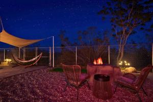un patio trasero con hamaca y fogata por la noche en Perfect Getaway withAmazing Views at Joshua Tree home, en Yucca Valley
