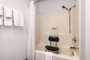 a bathroom with a shower and a black stool in a tub at Travelodge by Wyndham Depoe Bay in Depoe Bay