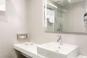 a white bathroom with a sink and a mirror at NH City Centre Amsterdam in Amsterdam