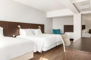 a hotel room with two beds and a table and chairs at NH City Centre Amsterdam in Amsterdam