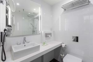 La salle de bains blanche est pourvue d'un lavabo et d'un miroir. dans l'établissement NH City Centre Amsterdam, à Amsterdam
