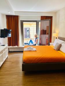 a child sitting on a bed in a hotel room at Prestige Rooms Chiaia in Naples