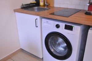 - un lave-linge blanc sous un comptoir dans la cuisine dans l'établissement Cosy studio paris13 10min to Louvre, à Paris