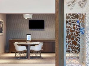 a waiting room with a table and chairs and a tv at Novotel London Stansted Airport in Stansted Mountfitchet