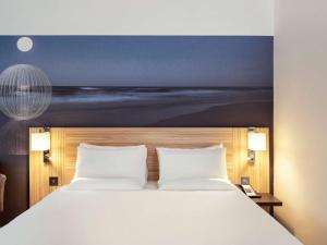 um quarto com uma cama com um quadro na parede em Novotel London Stansted Airport em Stansted Mountfitchet