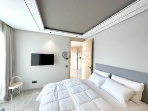 The Besty Ocean Suite-By Ayla Stay في الدار البيضاء: غرفة نوم بسرير كبير وتلفزيون على الحائط