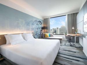 Habitación de hotel con cama blanca grande y escritorio. en Novotel Bangkok Sukhumvit 4 en Bangkok