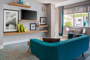 Hampton Inn Miami Beach - Mid Beach في ميامي بيتش: غرفة معيشة مع أريكة زرقاء وتلفزيون