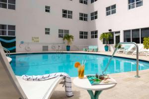 Hampton Inn Miami Beach - Mid Beach في ميامي بيتش: مسبح بطاولة وكرسي بجانب مبنى