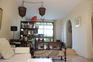 a living room with a couch and a book shelf with books at Chalet adosado en urbanización con piscina in Estepona