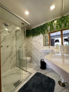 W łazience znajduje się szklana kabina prysznicowa i umywalka. w obiekcie VISTA PARK SUL COBERTURA DUPLEX w mieście Brasília