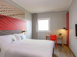 a hotel room with a large bed and a red chair at ibis Trujillo in Trujillo