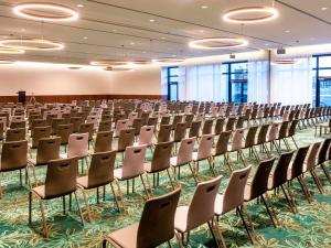 une grande chambre avec des rangées de chaises et un podium dans l'établissement Mövenpick Hotel Stuttgart Messe & Congress, à Stuttgart