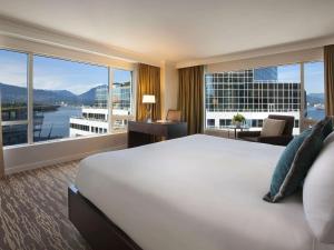 Habitación de hotel con cama grande y ventana grande. en Fairmont Waterfront en Vancouver