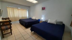 una habitación de hotel con 2 camas y una silla en Hotel Bluehouse, en Guatemala