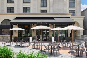 an outdoor patio with tables and chairs and umbrellas at The Hamilton Alpharetta, Curio Collection By Hilton in Alpharetta