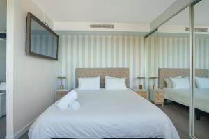 a bedroom with a large white bed and a mirror at 603 Newcastle Beachfront Apartment in Newcastle