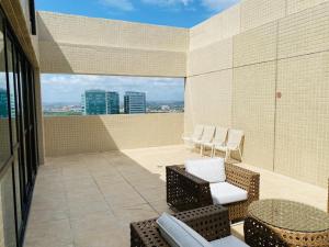 - un balcon avec des chaises et des tables dans un bâtiment dans l'établissement FLAT EXCELSIOR- PRÓXIMO SHOPPING RIOMAR, à Récife