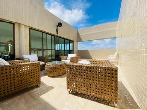 un patio avec des chaises et des tables en osier dans un bâtiment dans l'établissement FLAT EXCELSIOR- PRÓXIMO SHOPPING RIOMAR, à Récife