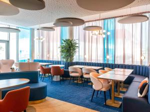 um restaurante com mesas, cadeiras e janelas em Mercure Dunkerque Centre Gare em Dunkerque