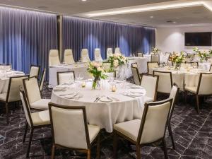 a banquet room with white tables and chairs with flowers at Mövenpick Hotel Hobart in Hobart