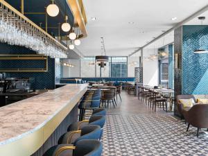 a restaurant with a bar with chairs and tables at Mercure Paignton Hotel in Paignton