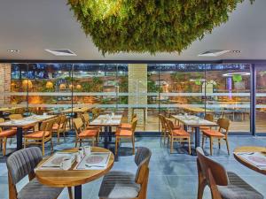 a restaurant with tables and chairs and a large window at Ibis Istanbul Airport in Istanbul