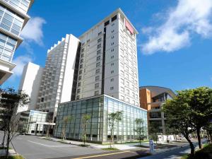 un edificio blanco alto en una calle de la ciudad en Mercure Hotel Okinawa Naha en Naha