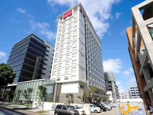 a tall white building with a red sign on it at Mercure Hotel Okinawa Naha in Naha